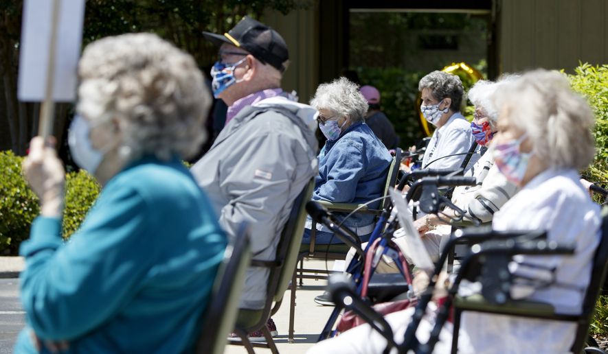 People wait outside for the start of Kathryn Camp's 100th birthday celebration at Hickory Valley Retirement Community on Monday, May 11, 2020 in Chattanooga, Tenn. Due to the coronavirus pandemic, Camp celebrated her birthday with a parade of vehicles, including a firetruck and Sheriff's vehicles, driving by and wishing her a happy birthday. (C.B. Schmelter/Chattanooga Times Free Press via AP)