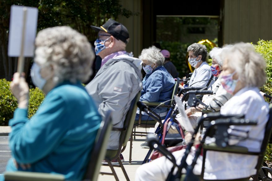 People wait outside for the start of Kathryn Camp's 100th birthday celebration at Hickory Valley Retirement Community on Monday, May 11, 2020 in Chattanooga, Tenn. Due to the coronavirus pandemic, Camp celebrated her birthday with a parade of vehicles, including a firetruck and Sheriff's vehicles, driving by and wishing her a happy birthday. (C.B. Schmelter/Chattanooga Times Free Press via AP)