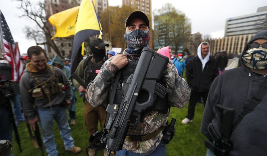 In this April 30, 2020, file photo, a protester carries his rifle at the State Capitol in Lansing, Mich. (AP Photo/Paul Sancya, File)