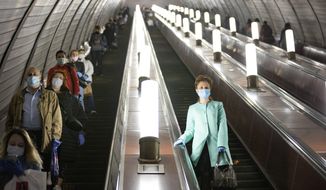 People wearing face masks and gloves to protect against coronavirus, observe social distancing guidelines as they go down the subway on the escalator in Moscow, Russia, Tuesday, May 12, 2020. From Tuesday onward, wearing face masks and latex gloves is mandatory for people using Moscow&#39;s public transport. President Vladimir Putin on Monday declared an end to a partial economic shutdown across Russia due to the coronavirus pandemic, but he said that many restrictions will remain in place. (AP Photo/Alexander Zemlianichenko)
