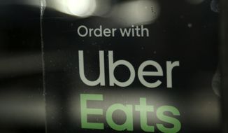 FILE - In this Nov. 6, 2019, file photo, a restaurant advertises Uber Eats in the Coconut Grove neighborhood in Miami. The Wall Street Journal reports that Uber is considering acquiring Grubhub in a deal that would give the companies control over a majority of the U.S. food delivery business. Citing anonymous sources, the newspaper says Uber approached Grubhub earlier this year with an all-stock takeover offer. (AP Photo/Lynne Sladky, File)