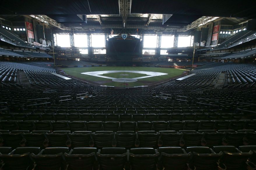 FILE - In this Tuesday, April 28, 2020, file photo, a darkened Chase Field, home of the Arizona Diamondbacks of baseball's National League, sits empty. Major League Baseball owners gave the go-ahead Monday, May 11, 2020, to making a proposal to the players' union that could lead to the coronavirus-delayed season starting around the Fourth of July weekend in ballparks without fans, a plan that envisions expanding the designated hitter to the National League for 2020. (AP Photo/Ross D. Franklin, File)