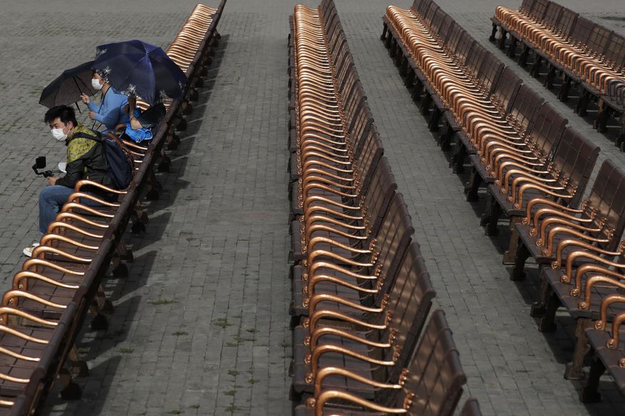 Visitors wearing protective face masks to help curb the spread of the new coronavirus take a rest on the bench at the Forbidden City in Beijing, Tuesday, May 12, 2020. China reported just one new coronavirus case, as the government presses ahead with reopening measures. Some students in Beijing have returned to their schools, and Shanghai Disneyland and the ancient Forbidden City have reopened to limited visitors with social distancing maintained. (AP Photo/Andy Wong)