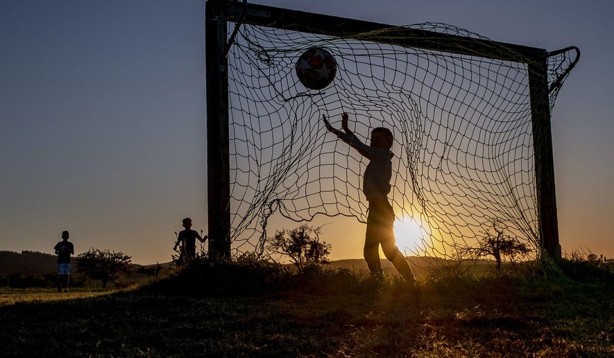 Children play soccer on a meadow with makeshift goals in Obernhain near Frankfurt, Germany, Tuesday, May 5, 2020. Due to the coronavirus playgrounds in German were closed until last Monday. (AP Photo/Michael Probst)