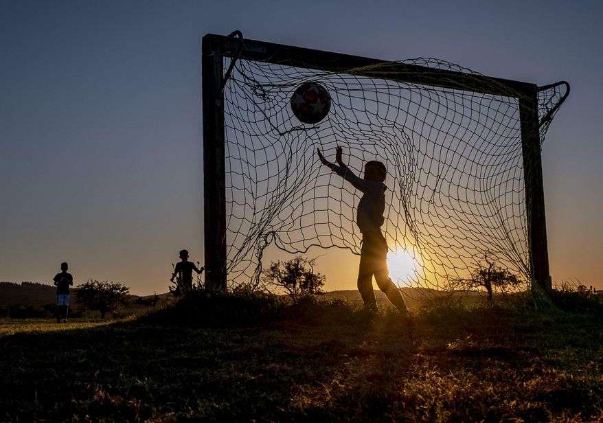 Children play soccer on a meadow with makeshift goals in Obernhain near Frankfurt, Germany, Tuesday, May 5, 2020. Due to the coronavirus playgrounds in German were closed until last Monday. (AP Photo/Michael Probst)