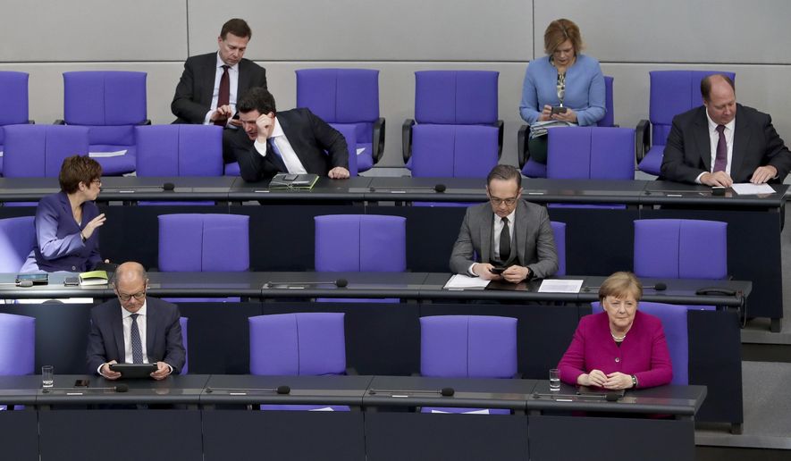 FILE - In this Thursday, April 23, 2020 file photo, German Chancellor Angela Merkel, front right, and ministers of the German government attend a meeting of the German federal parliament, Bundestag, at the Reichstag building in Berlin, Germany. Across Europe and beyond, parliaments and governments have had to adapt their operations to stop the virus spreading through the corridors of power. Social distancing, online debates, masks, plexiglass, hazard tape, each country's legislature has its own measures. (AP Photo/Michael Sohn, File)