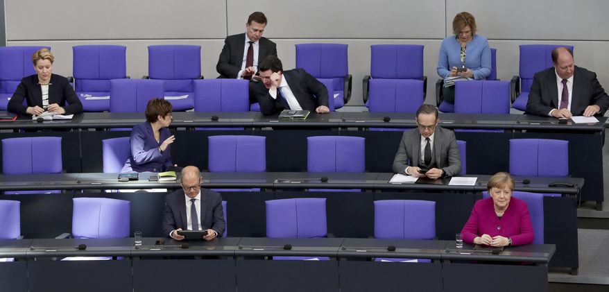 FILE - In this Thursday, April 23, 2020 file photo, German Chancellor Angela Merkel, front right, and ministers of the German government attend a meeting of the German federal parliament, Bundestag, at the Reichstag building in Berlin, Germany. Across Europe and beyond, parliaments and governments have had to adapt their operations to stop the virus spreading through the corridors of power. Social distancing, online debates, masks, plexiglass, hazard tape, each country's legislature has its own measures. (AP Photo/Michael Sohn, File)