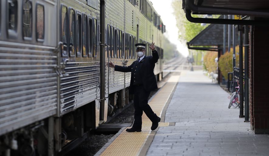 A Metra conductor signals for all clear at the Glenview Amtrak/Metra Station in Glenview, Ill., Wednesday, May 13, 2020. All customers are now required to wear a mask or face covering while using Metra, a commuter rail system in the Chicago metropolitan area serving the city of Chicago and surrounding suburbs. (AP Photo/Nam Y. Huh)