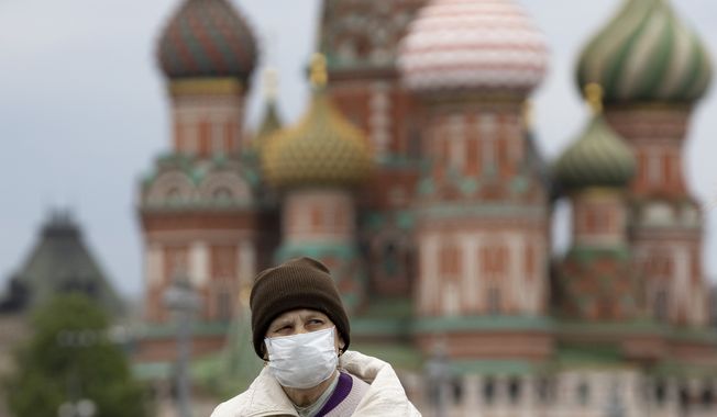 A woman wearing face mask to protect against coronavirus, walks near Red Square with St. Basil&#x27;s Cathedral in the background in Moscow, Russia, Tuesday, May 12, 2020. (AP Photo/Alexander Zemlianichenko)