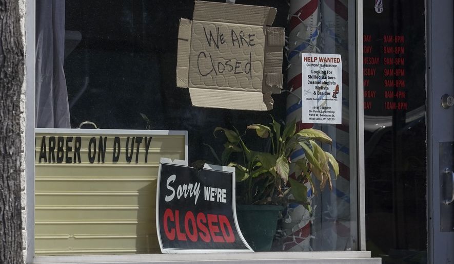 Closed signs are seen in some businesses Wednesday May 13, 2020, in Milwaukee. The new coronavirus causes mild or moderate symptoms for most people, but for some, especially older adults and people with existing health problems, it can cause more severe illness or death. (AP Photo/Morry Gash)