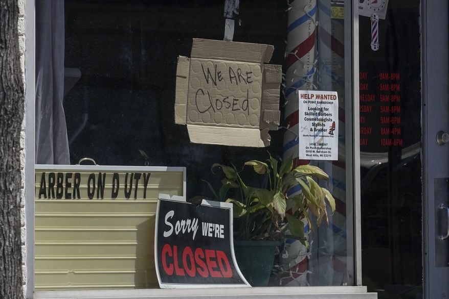 Closed signs are seen in some businesses Wednesday May 13, 2020, in Milwaukee. The new coronavirus causes mild or moderate symptoms for most people, but for some, especially older adults and people with existing health problems, it can cause more severe illness or death. (AP Photo/Morry Gash)