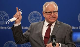 FILE - In an April 30, 2020 file photo, Minnesota Gov. Tim Walz answers questions while holding his mask at a news conference inside the Department of Public Safety in St. Paul, Minn. Walz said Wednesday, May 13, 2020 he will let his stay-at-home order expire as scheduled Monday, though he’ll leave key restrictions in place to keep up Minnesota’s fight against the COVID-19 pandemic. (Evan Frost/Minnesota Public Radio via AP, Pool, File)