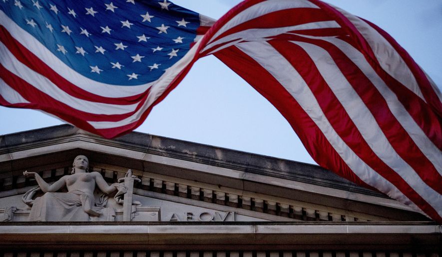 FILE - In this March 22, 2019 file photo, an American flag flies outside the Department of Justice in Washington. The Department of Justice says in a statement that hackers have been attempting to obtain intellectual property and public health data related to vaccines, treatments, and testing. (AP Photo/Andrew Harnik)