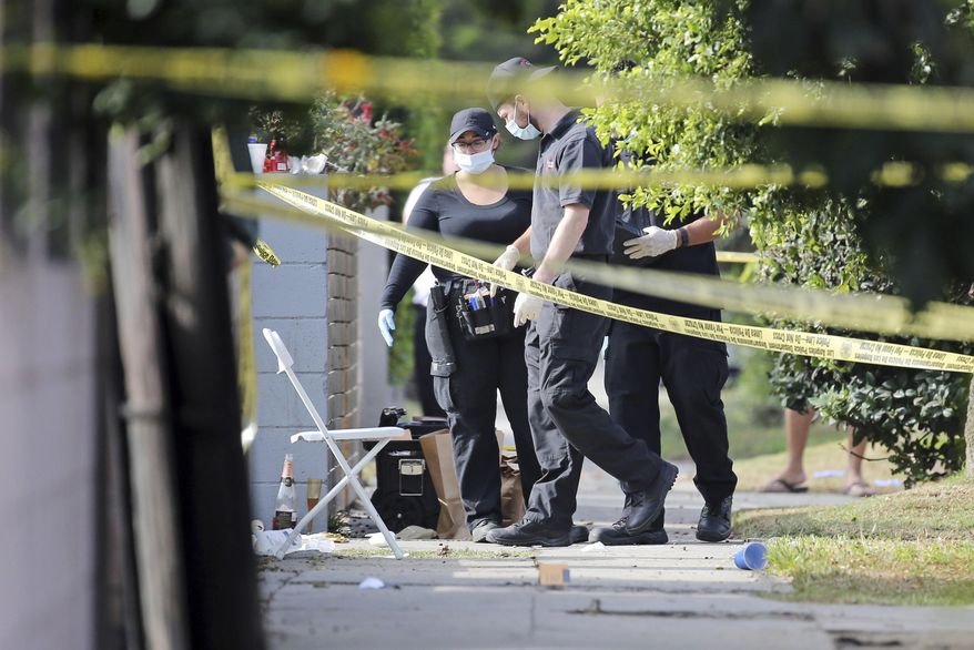 FILE - In this Oct. 15, 2016 file photo, Los Angeles police investigators work the scene of a fatal shooting in the Crenshaw District of Los Angeles. Detectives nationwide are grappling with changes the coronavirus has wrought on their investigations. Cold cases are getting colder, plainclothes investigators are digging out their dusty uniforms for patrol duty, and detectives are struggling to find new ways to connect with victims through thick masks. Even as police departments report major decreases in crime statistics thanks to stay-at-home orders, authorities say enough wrongdoing abounds to keep cops busy. And some detective work must still be in-person and hands-on, despite COVID-19. (AP Photo/Reed Saxon, File)
