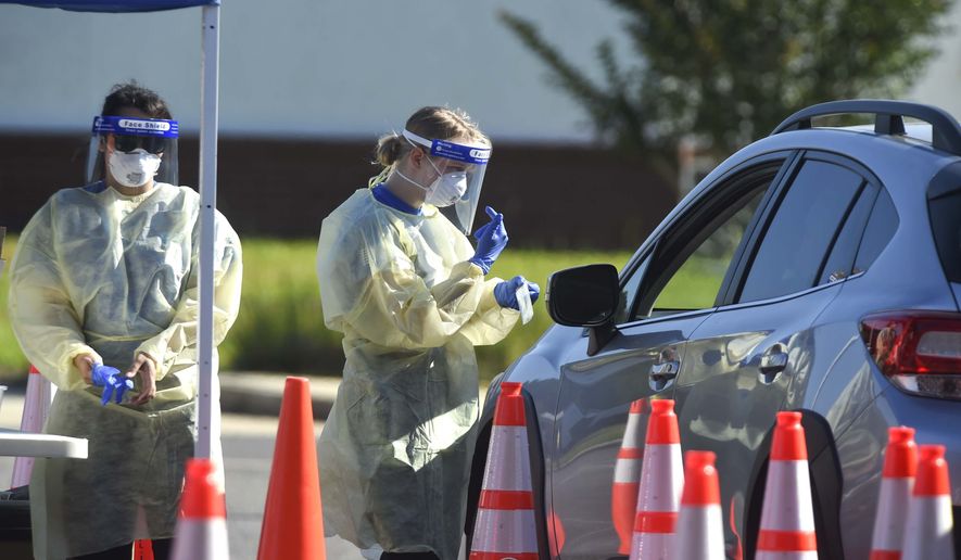 A medical technician talks to a patient at a drive-thru COVID-19 testing site, Thursday, May 14, 2020 in Crestview, Fla. Officials in Florida panhandle's Okaloosa County have begun offering regular free drive-thru COVID-19 testing for county residents at various sites around Okaloosa County.(Devon Ravine/Northwest Florida Daily News via AP)