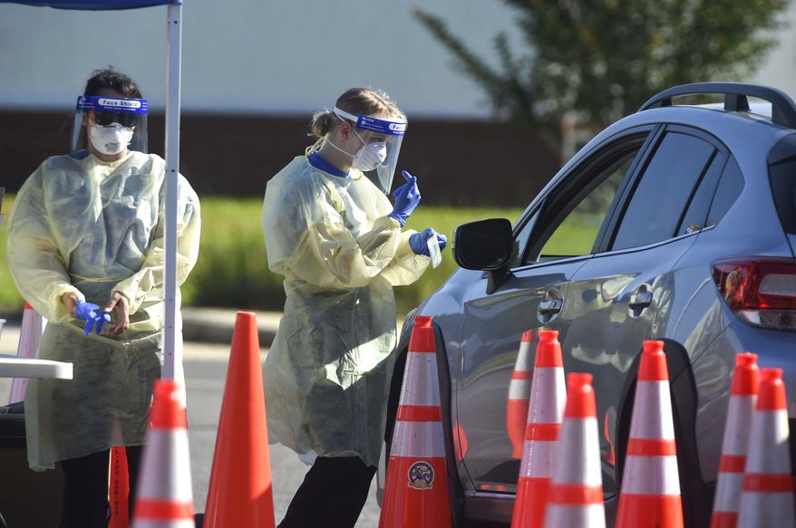 A medical technician talks to a patient at a drive-thru COVID-19 testing site, Thursday, May 14, 2020 in Crestview, Fla. Officials in Florida panhandle's Okaloosa County have begun offering regular free drive-thru COVID-19 testing for county residents at various sites around Okaloosa County.(Devon Ravine/Northwest Florida Daily News via AP)