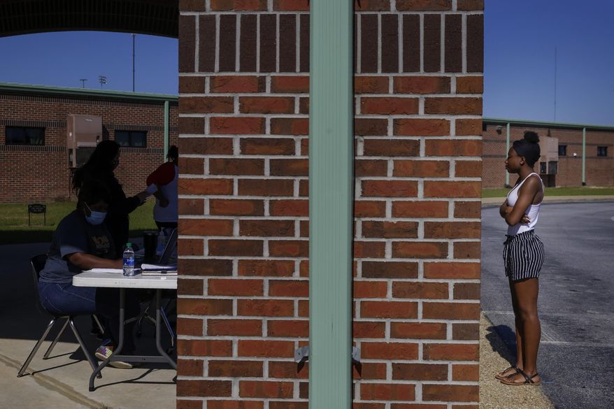 In this Thursday, May 7, 2020 photo, Azandria Torbert, stands in line for graduation information at Chattahoochee County High School after the school district called an early end to the school year, in Cusseta, Ga. The small district in rural Georgia is among many around the U.S. that have pulled the plug on distance learning, all citing familiar reasons. It's too stressful, the lack of devices and internet access is too much to overcome, and what students get from it just isn't worth the struggle. (AP Photo/Brynn Anderson)