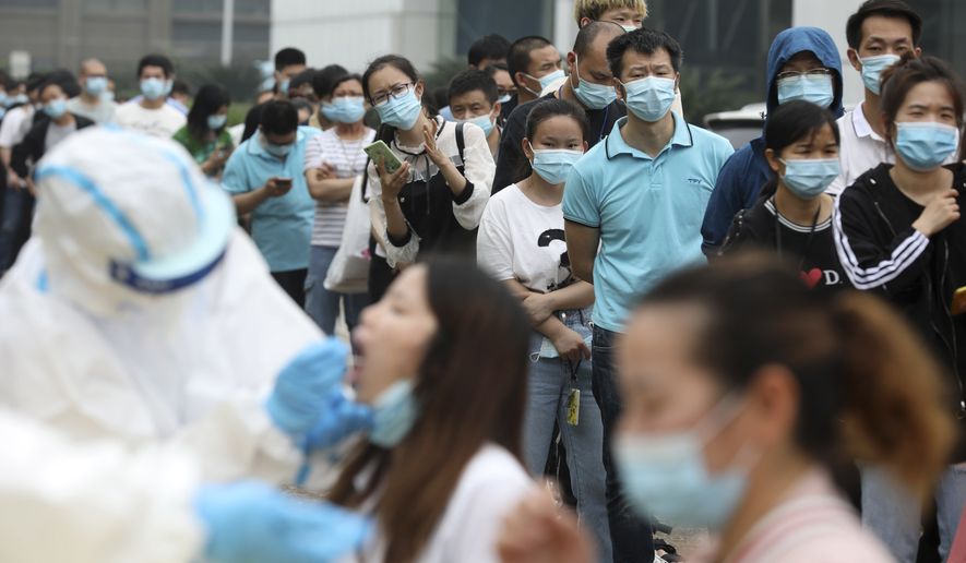 Workers line up for medical workers to take swabs for the coronavirus test at a large factory in Wuhan in central China's Hubei province Friday, May 15, 2020. Wuhan have begun testing inhabitants for the coronavirus as a program to test everyone in the Chinese city of 11 million people in 10 days got underway. (Chinatopix Via AP)
