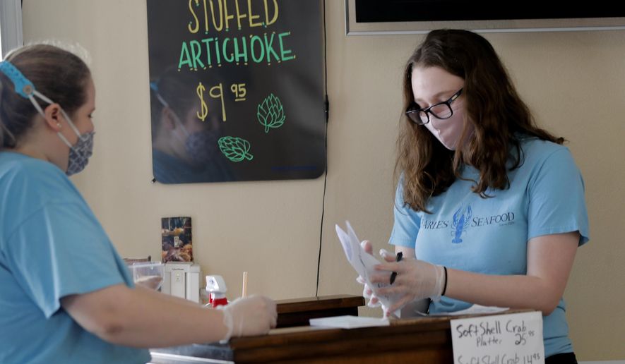 Employees Elise Bourg , right, and Emily Martinez, fold menus at Charles Seafood Restaurant, serving customers indoors for the first time since the state shutdown, in Harahan, La., Friday, May 15, 2020. Once a hot spot for coronavirus infections, Louisiana is officially easing up Friday on economically devastating business closures and public gathering restrictions that Gov. John Bel Edwards credits with slowing the spread of the virus. (AP Photo/Gerald Herbert)