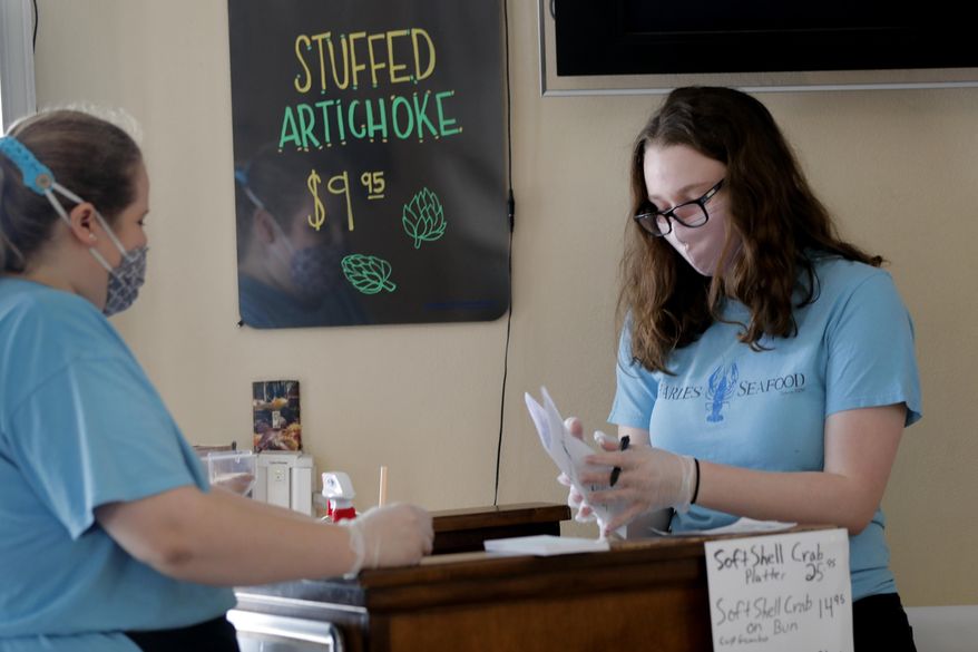 Employees Elise Bourg , right, and Emily Martinez, fold menus at Charles Seafood Restaurant, serving customers indoors for the first time since the state shutdown, in Harahan, La., Friday, May 15, 2020. Once a hot spot for coronavirus infections, Louisiana is officially easing up Friday on economically devastating business closures and public gathering restrictions that Gov. John Bel Edwards credits with slowing the spread of the virus. (AP Photo/Gerald Herbert)
