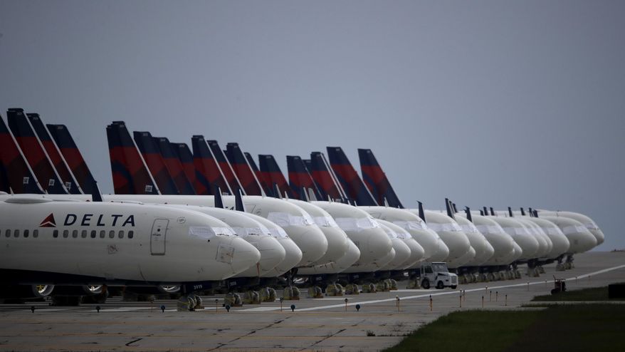 Several dozen mothballed Delta Air Lines jets are parked on a closed runway at Kansas City International Airport on Thursday, May 14, 2020, in Kansas City, Mo. The planes, some of the approximately 90 Delta jets parked at the airport, are among the thousands of passenger planes taken out of service worldwide as travel restrictions and stay-at-home orders due to the new coronavirus has drastically reduced air travel. (AP Photo/Charlie Riedel)