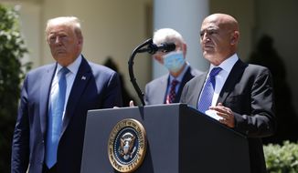 President Donald Trump, left, listens as Moncef Slaoui, a former GlaxoSmithKline executive, speaks about the coronavirus in the Rose Garden of the White House, Friday, May 15, 2020, in Washington. (AP Photo/Alex Brandon)