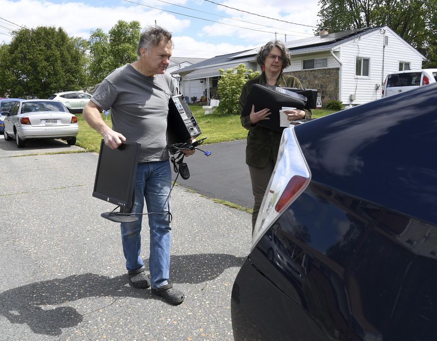 In this Saturday, May 9, 2020 photo, Ed Witles, left, who has been repairing and repurposing discarded or donated older computers and donating them to Anne Arundel County students with the help of Annapolis High School teacher Romey Pittman, right, place computers in a car in Glen Burnie, Md. (Paul W. Gillespie/The Baltimore Sun via AP)