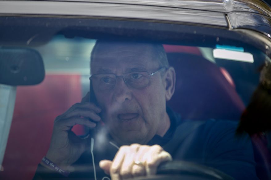 Former Gov. Paul LePage, sitting in a Lexus SC 430, uses his cell phone to address protesters rallying against the executive orders by Gov. Janet Mills to keep some Maine businesses closed to help prevent the spread of coronavirus, Saturday, May 16, 2020, in Augusta, Maine. His call was broadcast over speakers set up at the nearby rally. LePage, now a resident of Florida, stayed in his car parked near the rally. A speaker at the event said the former governor was quarantining. (AP Photo/Robert F. Bukaty)