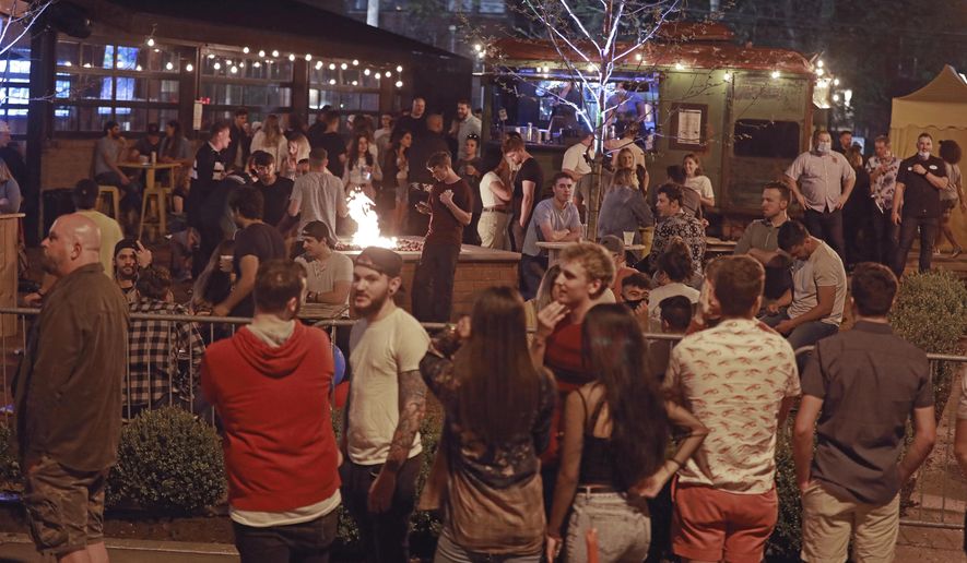 A crowd gathers to drink at Standard Hall, a bar, on Friday, May 15, 2020 in Columbus, Ohio. Ohio restaurants have the option beginning Friday to offer outdoor dining, the next step toward resuming normal business operations under Republican Gov. Mike DeWine’s state reopening plan during the coronavirus pandemic. The bar's owners, Corso Ventures, told WBNS-TV "Standard Hall has exactly 45 tables on the patio, spaced 6ft apart. Based on the guidelines set forth by the state, we are not allowing parties of more than 10 at each table. (Doral Chenoweth/The Columbus Dispatch via AP)