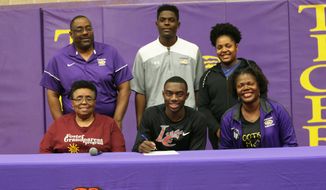 In this Feb. 6, 2020, photo, Thibodaux High School senior Tyren Young, seated in the middle, poses with his family as he has accepted a college scholarship to play football at Louisiana College during National Signing Day, in Thibodaux, La. (Chris Singleton/The Courier via AP)