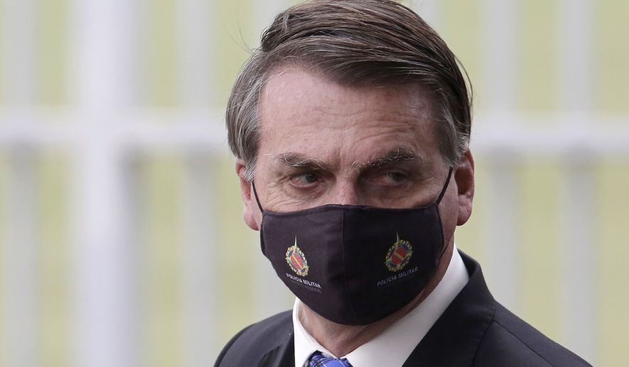 Brazilian President Jair Bolsonaro wears a mask due to the COVID-19 pandemic as he leaves his official residence, Alvorada palace, in Brasilia, Brazil, Monday, May 18, 2020. The logo on the mask reads &quot;Military Police. Federal District.&quot; (AP Photo/Eraldo Peres)