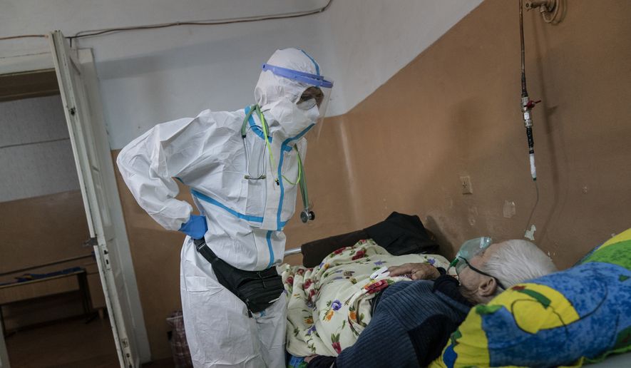 In this photo taken on Saturday, May 9, 2020, Dr. Olha Kobevko speaks to a patient suspected of having coronavirus at the regional hospital in Chernivtsi, Ukraine. The hospital lacks a centralized oxygen supply and has to rely mostly on refillable oxygen masks, reflecting a pitiful state of Ukraine&#39;s underfunded health care system that was quickly overwhelmed by the coronavirus even with a relatively low number of infections. (AP Photo/Evgeniy Maloletka)