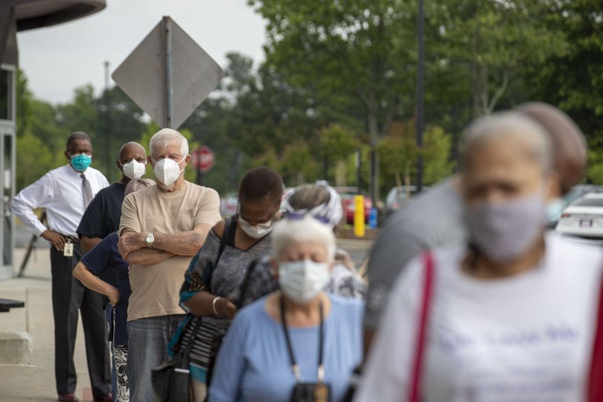 Voters wearing face masks strand in line outside of the Gwinnett County Voter Registration and Elections Office in order to participate in early voting for Georgia's primary election in Lawrenceville, Ga., Monday, May 18, 2020. Early voting began Monday and will last three-weeks. Georgia's Election Day is Tuesday, June 9. (Alyssa Pointer/Atlanta Journal-Constitution via AP)
