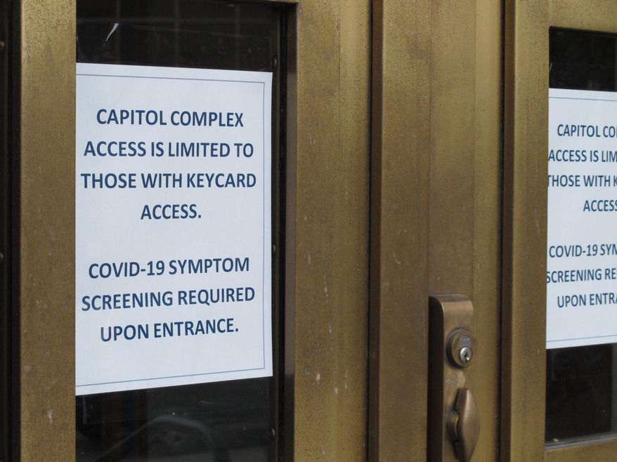 A sign is posted on the front doors of the Alaska Capitol on Monday, May 18, 2020, in Juneau, Alaska. The Alaska Legislature planned to reconvene Monday to address use of federal coronavirus relief funds, with protocols in place aimed at guarding against the virus. (AP Photo/Becky Bohrer)