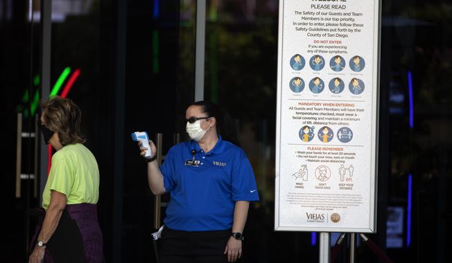 An official reads the temperature of a woman at the entrance to the Viejas Casino and Resort as it reopens Monday, May 18, 2020, in Alpine, Calif. The casino is one of several on tribal lands in Southern California set to reopen this week. (AP Photo/Gregory Bull)