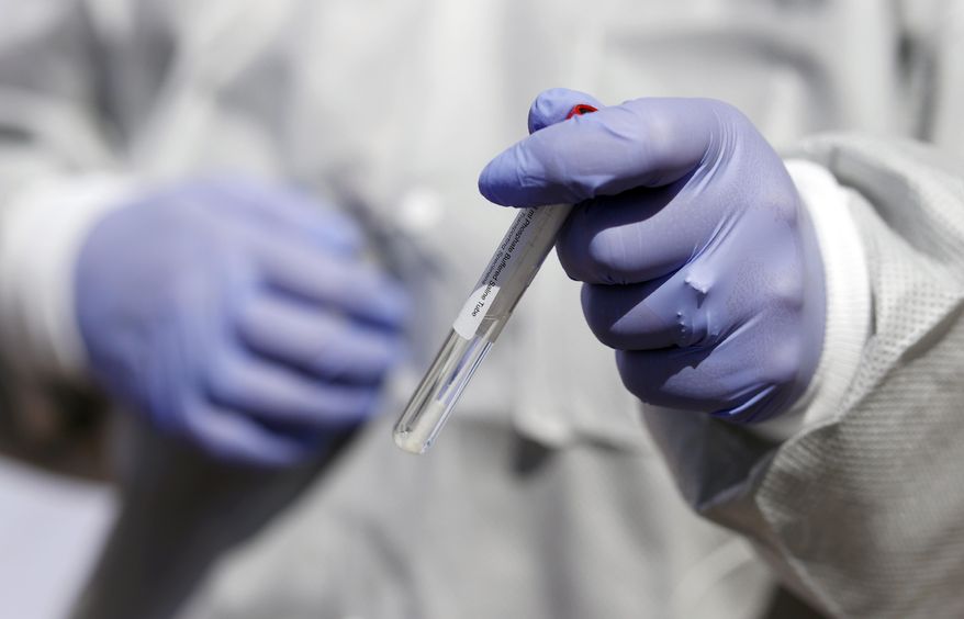 The swab used for a nasal test for the new coronavirus on Colorado Governor Jared Polis, not in the picture, is held by registered nurse Stephanie Campbell during a news conference outside the Stride Community Health Center Monday, May 18, 2020, in Wheat Ridge, Colo. (AP Photo/David Zalubowski)