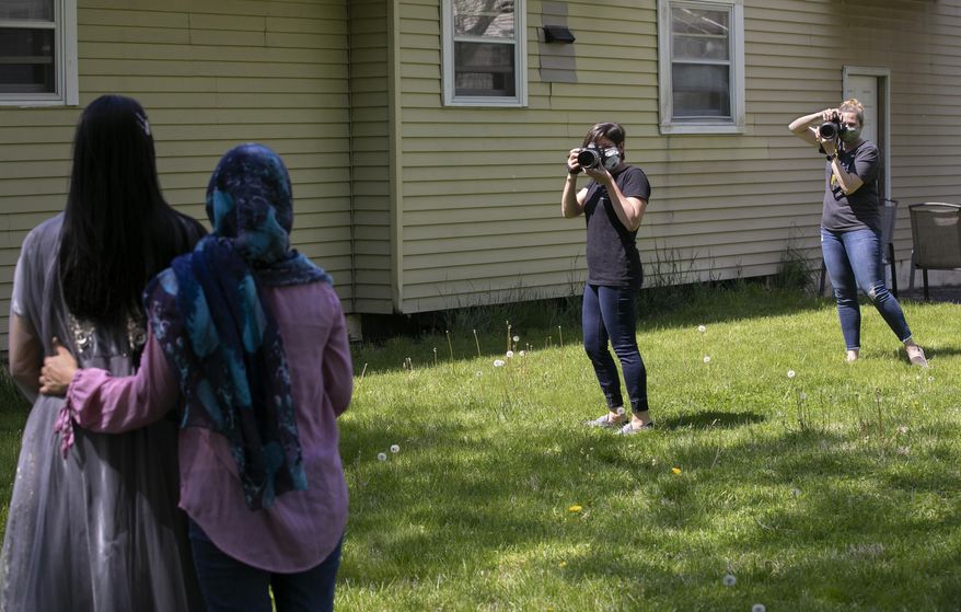 In this Friday, May 15, 2020 photo, photographers Jennifer Dougan, left, and Christy Mitchell, of Wallingford, photograph Lyman Hall High School student Imaan Raza, 18, and mother Umera Raza at their residence in Wallingford, Conn. Dougan and Mitchell are offering Lyman Hall High School seniors complimentary mini-prom photo shoots as a silver lining to the pandemic canceling the event. (Dave Zajac/Record-Journal via AP)