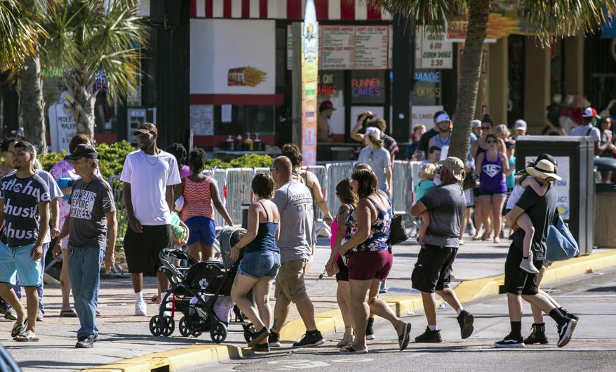 Groups cross Ocean Boulevard on Saturday, May 16, 2020, in Myrtle Beach, S.C.. With hotels, beaches, shopping and restaurants reopening along the Grand Strand, tourist season kicked off this weekend despite coronavirus concerns. (Jason Lee/The Sun News via AP)