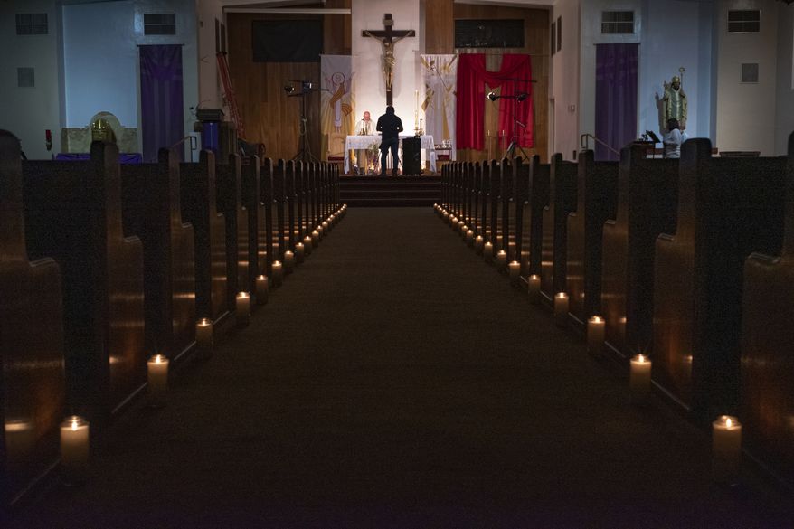 FILE - In this April 11, 2020, file photo, a person films pastor Nicolas Sanchez, center left, celebrating Easter Vigil Mass at his church decorated with candles and pictures sent by his parishioners attached to their pews at St. Patrick Church in North Hollywood, Calif. The head of the federal Justice Department's Civil Rights Division told Gov. Gavin Newsom Tuesday, May 19, 2020, that his plan to reopen California discriminates against churches. (AP Photo/Damian Dovarganes)