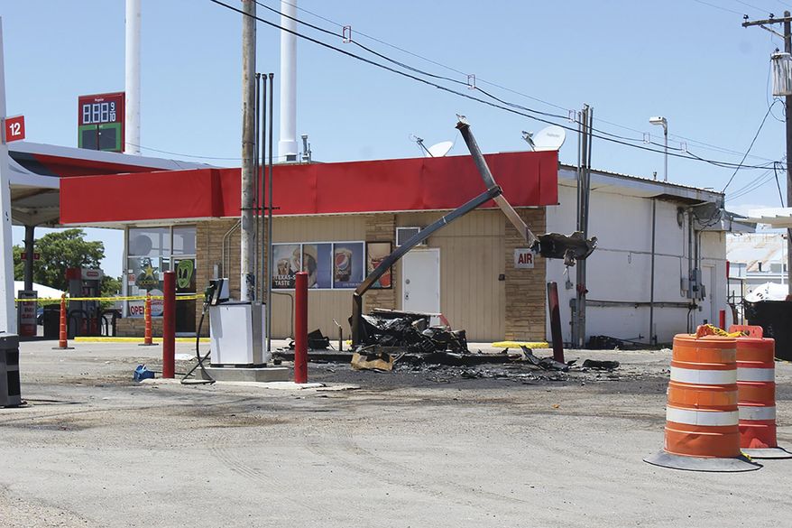 In this Monday, May 18, 2020, photo is a charred fuel pump at a gas station in Roswell, N.M. The pump was damaged when a pickup truck being pursued by a Chaves County sheriff's deputy crashed and sparked a fire. The suspect who evaded authorities remains at large after surviving an explosion at a local gas station that ended a police pursuit and injured a woman, authorities said. (Alex Ross/Roswell Daily Record via AP)