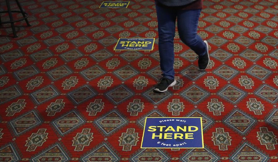 Signs to encourage social distancing are seen on the floor Tuesday, May 12, 2020, at Thunderbird Casino in Norman, Okla. The Casino, operated by the Absentee Shawnee Tribe, has reopened for business with about one-third of capacity allowed and social distancing guidelines. (AP Photo/Sue Ogrocki)