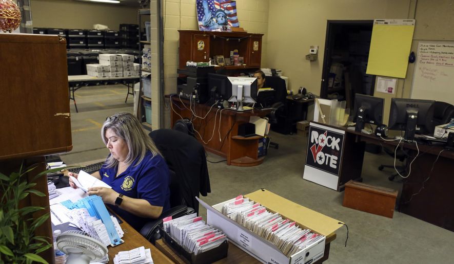 In this Monday, April 20, 2020 photo, inventory clerk Teresa Barajas, left, and warehouse supervisor Maribel Juarez work on elections business as part of a skeleton staff, as the department navigates elections during the COVID-19 pandemic at the Cameron County Elections Department in Brownsville, Texas. (Denise Cathey/The Brownsville Herald via AP)