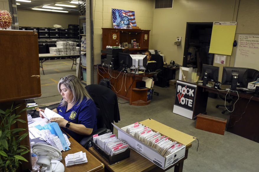 In this Monday, April 20, 2020 photo, inventory clerk Teresa Barajas, left, and warehouse supervisor Maribel Juarez work on elections business as part of a skeleton staff, as the department navigates elections during the COVID-19 pandemic at the Cameron County Elections Department in Brownsville, Texas. (Denise Cathey/The Brownsville Herald via AP)