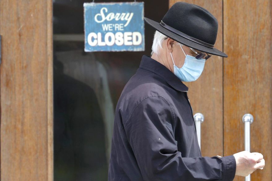 A man walks past a closed business. A Michigan businessman is urging the public to speak up by promoting "Take Yourself to Work Day." (Associated Press)