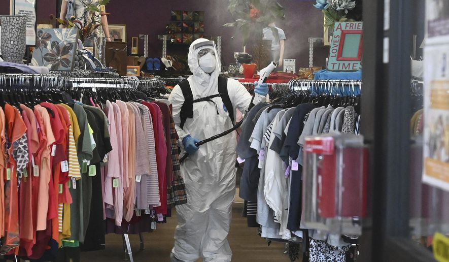 A crew equipped with electrostatic sprayers cleans a Goodwill store with a hydrogen peroxide disinfectant cleaner after several employees tested positive for COVID-19, on Tuesday, May 19, 2020, in Colorado Springs, Colo. The store is temporarily closed and no reopening date has yet been announced. But all of the other Goodwill Stores in area are reopened except the Austin Bluffs store here and the W. Colorado Ave. store. (Jerilee Bennett/The Gazette via AP)