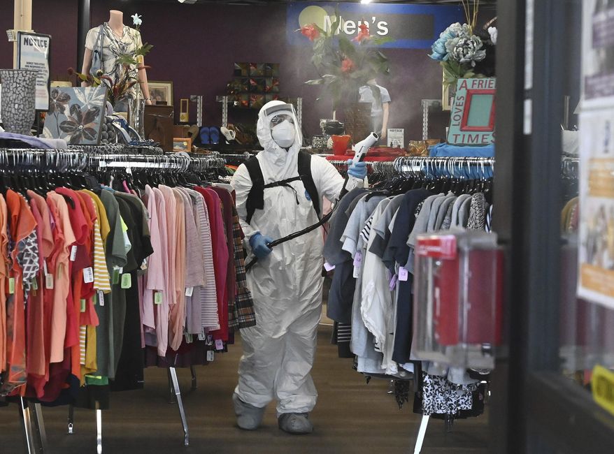 A crew equipped with electrostatic sprayers cleans a Goodwill store with a hydrogen peroxide disinfectant cleaner after several employees tested positive for COVID-19, on Tuesday, May 19, 2020, in Colorado Springs, Colo. The store is temporarily closed and no reopening date has yet been announced. But all of the other Goodwill Stores in area are reopened except the Austin Bluffs store here and the W. Colorado Ave. store. (Jerilee Bennett/The Gazette via AP)