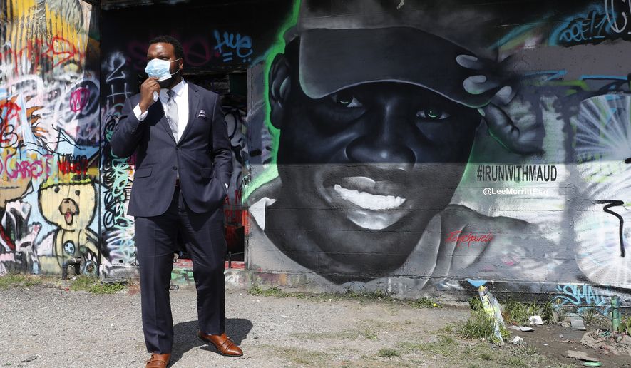 Lee Merritt, a lawyer representing the family of Ahmaud Arbery, gets a close look of a mural in the likeness of Arbery painted by artist Theo Ponchaveli in Dallas, Saturday, May 9, 2020. Arbery's mother, Wanda Cooper Jones, has said she thinks her son, a former high school football player, was jogging for exercise before he was killed on Feb. 23. After a video of the shooting emerged on social media, the Georgia Bureau of Investigation, on Wednesday, arrested Gregory McMichael, 64, and his son, Travis McMichael, 34, and they were jailed on murder and aggravated assault charges. (AP Photo/Tony Gutierrez)
