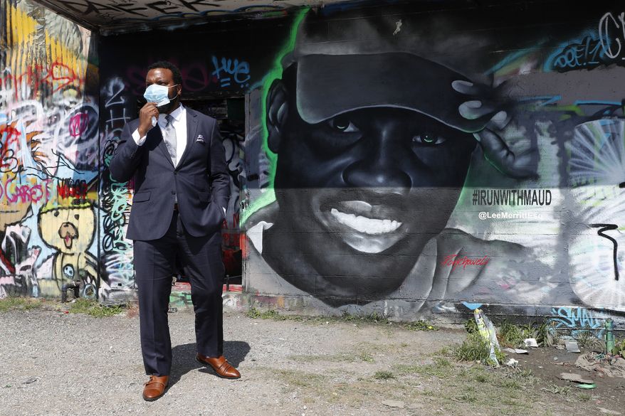 Lee Merritt, a lawyer representing the family of Ahmaud Arbery, gets a close look of a mural in the likeness of Arbery painted by artist Theo Ponchaveli in Dallas, Saturday, May 9, 2020. Arbery's mother, Wanda Cooper Jones, has said she thinks her son, a former high school football player, was jogging for exercise before he was killed on Feb. 23. After a video of the shooting emerged on social media, the Georgia Bureau of Investigation, on Wednesday, arrested Gregory McMichael, 64, and his son, Travis McMichael, 34, and they were jailed on murder and aggravated assault charges. (AP Photo/Tony Gutierrez)