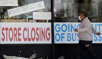 A man looks at signs of a closed store due to COVID-19 in Niles, Ill., Thursday, May 21, 2020. The U.S. economy shrank in the first quarter amid record-high inflation, a sharp reversal that President Biden blamed on &quot;technical factors&quot; as he tried to tamp down concerns of a recession in the midterm election year. (AP Photo/Nam Y. Huh)