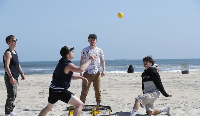 A group plays a game of spike ball at Jones Beach amid the coronavirus pandemic, Thursday, May 21, 2020, in Wantagh, N.Y. As pandemic lockdowns ease across the United States, millions of Americans are set to take tentative steps outdoors to celebrate Memorial Day, the traditional start of summer. But public health officials are concerned that if people congregate in crowds or engage in other risky behaviors, the long weekend could cause the coronavirus to come roaring back. (AP Photo/Kathy Willens)